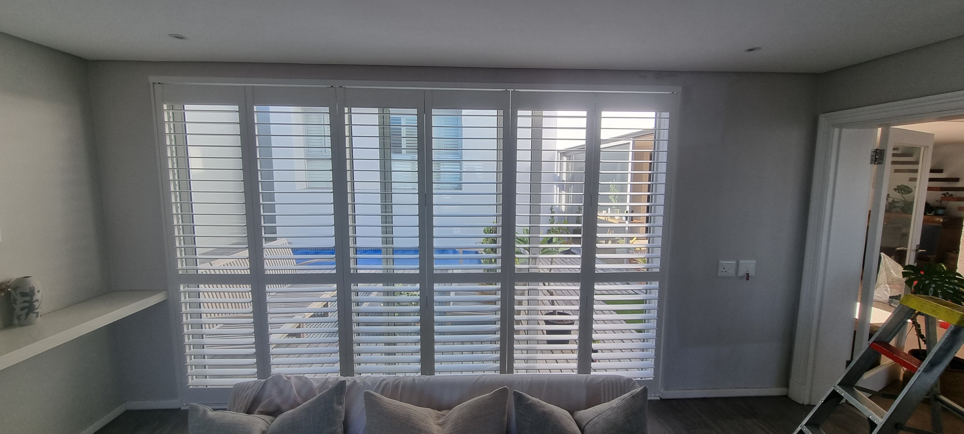Thermowood PVC shutters open onto a lounge with a pool view